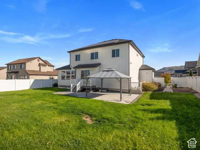 Expansive backyard featuring a manicured lawn, a concrete patio, and a white privacy fence