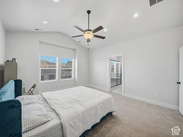 Vaulted ceiling with a ceiling fan, recessed lighting, carpet flooring, and an adjoining bathroom with a glass-enclosed shower