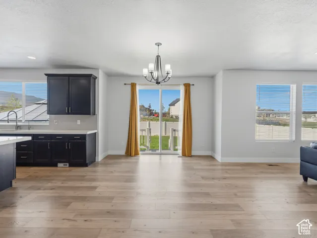 Open-concept living area with wood-finish flooring, a contemporary chandelier, and sliding glass door access to the exterior
