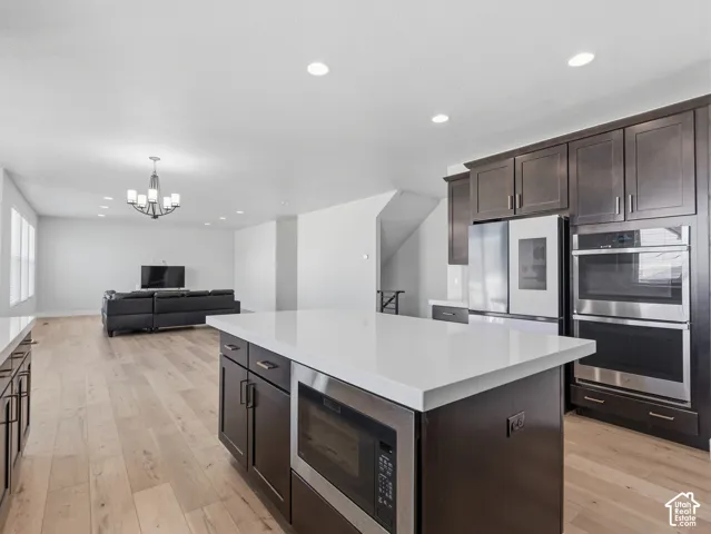 Open-concept living area with light wood-finish flooring, recessed lighting, and a contemporary chandelier