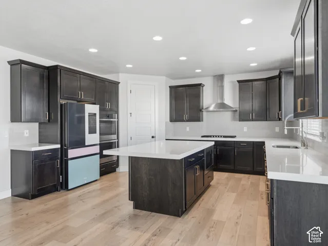 Spacious kitchen featuring dark wood-finish cabinetry, light countertops, wood-finish flooring, a stainless steel range hood, and recessed lighting