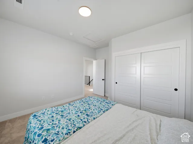 Carpeted flooring, white walls, built-in closet with sliding panel doors, recessed ceiling light, and an open doorway