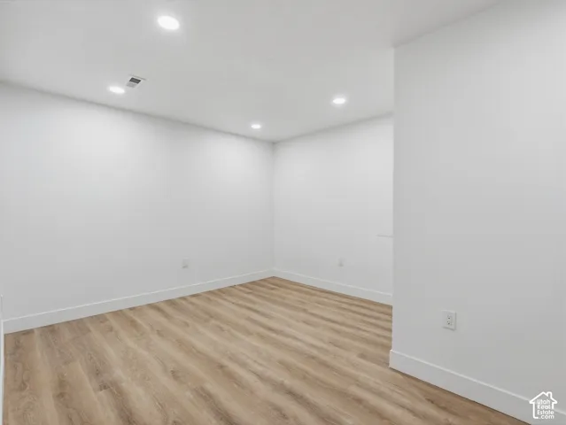 Recessed lighting illuminating the white walls and wood-finish flooring