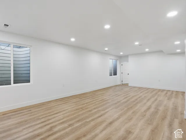 Expansive room featuring wood-finish flooring, recessed ceiling lighting, and multiple windows