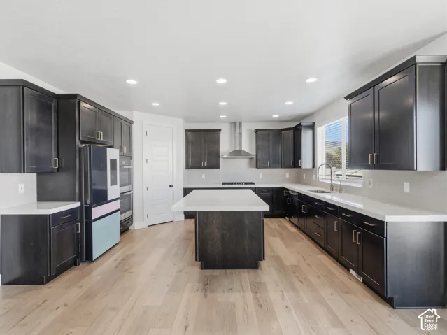 Spacious kitchen featuring dark wood-finish cabinetry, light countertops, wood-finish flooring, a central island, and stainless steel appliances