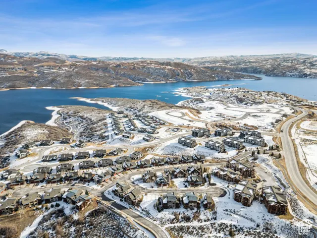 Expansive waterfront community with varied architectural styles, including multi-unit and single-structure dwellings, situated against a mountainous backdrop