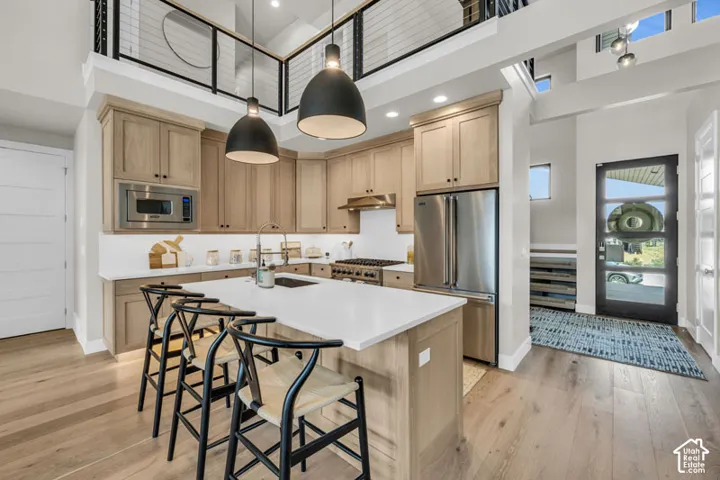 Kitchen featuring wood-finish cabinetry, stainless steel appliances, a center island with countertop seating, and recessed lighting