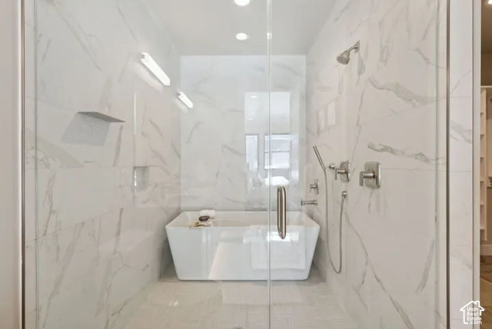 Glass-enclosed shower with a freestanding soaking tub, dual shower heads, and an integrated shelf