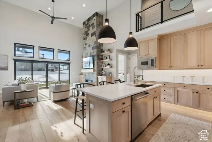 Open-concept great room featuring a soaring ceiling, stone-clad fireplace, and wood-finish flooring