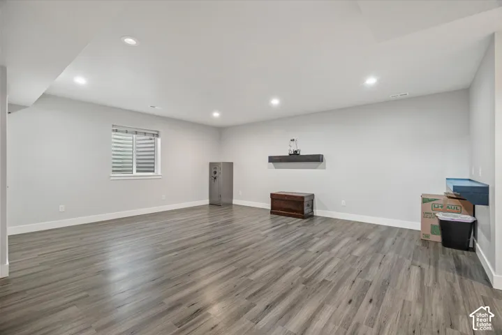 Recessed lighting, wood-finish flooring, white walls, and a window with blinds