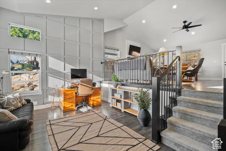 Two-story accent wall with wainscoting, recessed lighting, wood-finish flooring, and a black wrought iron railing
