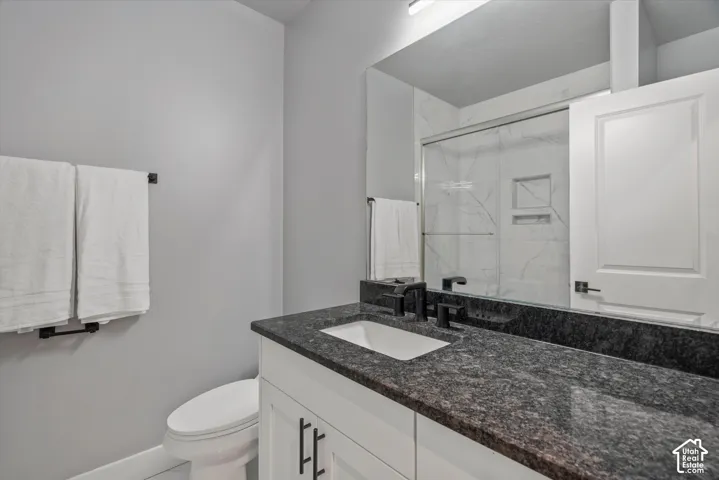 White vanity with dark stone countertop, undermount sink, and matte black fixtures
