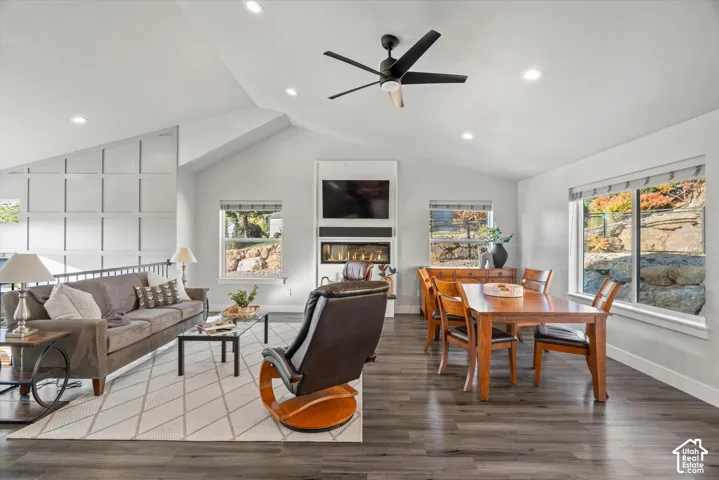 Vaulted ceilings with recessed lighting, wood-finish flooring, a contemporary fireplace with a built-in media center, and expansive windows