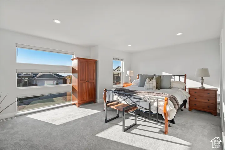 Recessed ceiling lighting, light gray carpeting, and multiple windows with horizontal blinds
