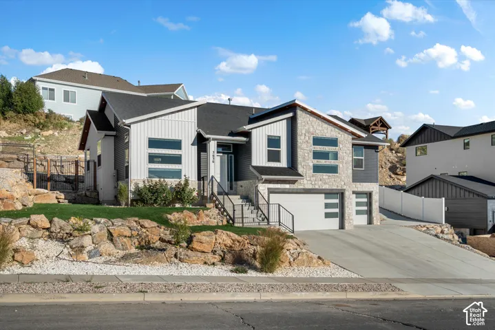 Modern exterior with stone and vertical siding accents, two garage doors with horizontal window details, and a sloped driveway
