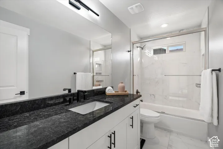 Bathroom featuring a white vanity with black hardware, dark granite-finish countertop, under-mount sink, and matte black fixtures