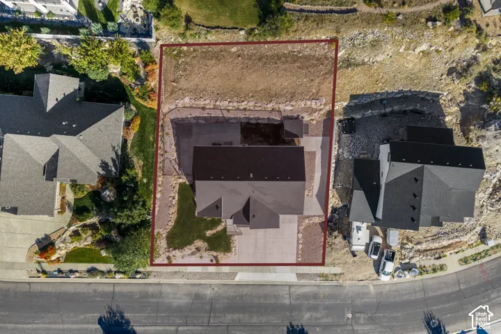 Property featuring a dark shingle roof, concrete driveway, and established landscaping