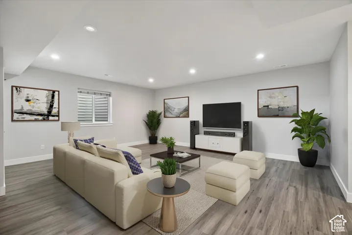 Recessed lighting illuminates this room featuring wood-finish flooring and light-toned walls