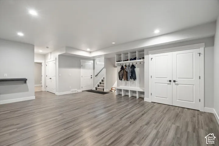 Spacious room featuring wood-finish flooring, recessed lighting, and a built-in storage bench with shelving