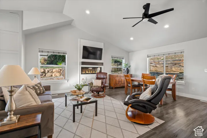 Vaulted ceilings with recessed lighting, linear electric fireplace, built-in media center, wood-finish flooring, and a modern ceiling fan