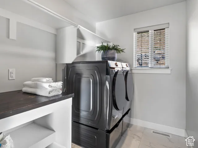 Laundry area with integrated shelving, dark wood-finish countertop, and a window with blinds