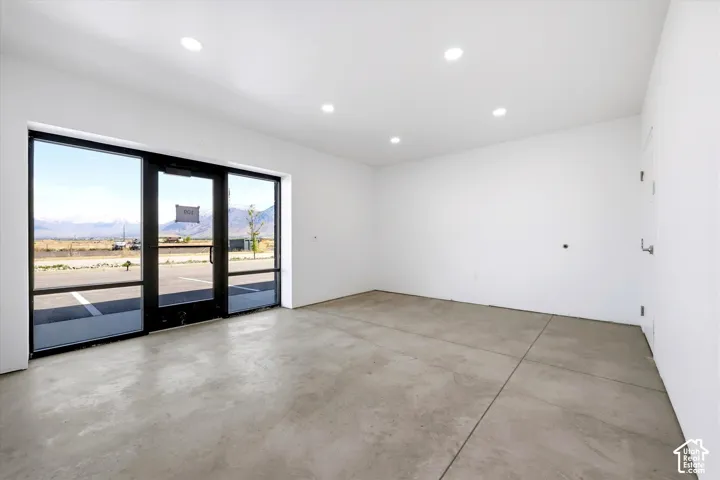 Expansive floor-to-ceiling windows with black framing, concrete flooring, recessed lighting, and white painted walls