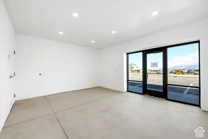 Recessed lighting illuminates an open interior with concrete flooring and a large storefront window