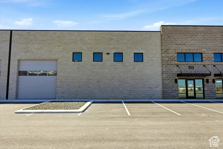 Block construction exterior with multiple windows, a roll-up door, and commercial entry doors