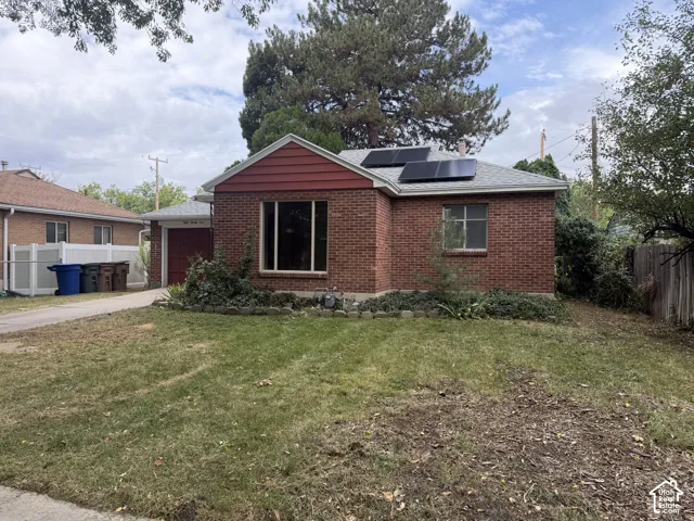 Brick exterior with a gabled roofline, solar panels, and a large front window