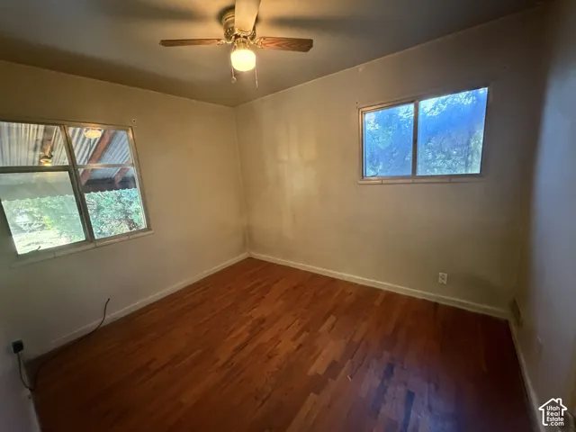 Wood-finish flooring with a ceiling fan light fixture and two windows