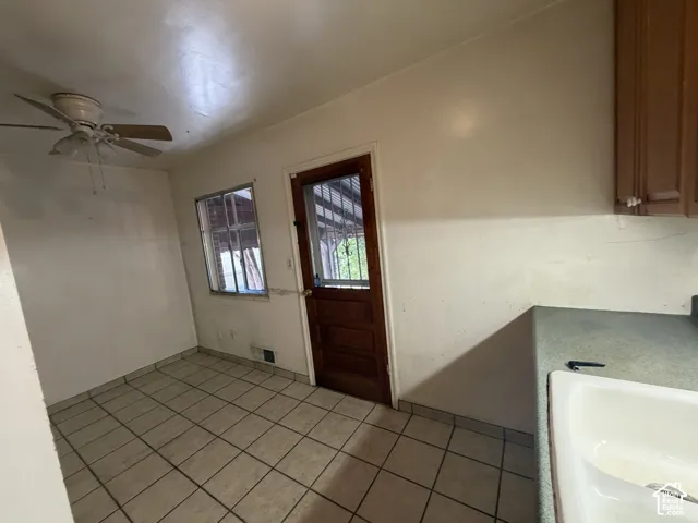 Tiled flooring, ceiling fan, wood-finish cabinetry, countertop, and a single-basin sink