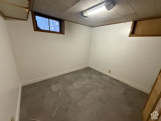 Interior space featuring white walls and a grey-toned floor with varied patterning