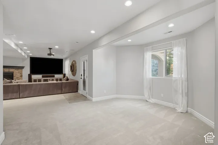 Spacious interior featuring recessed lighting, a stone-surround fireplace, and a glass-paneled exterior door