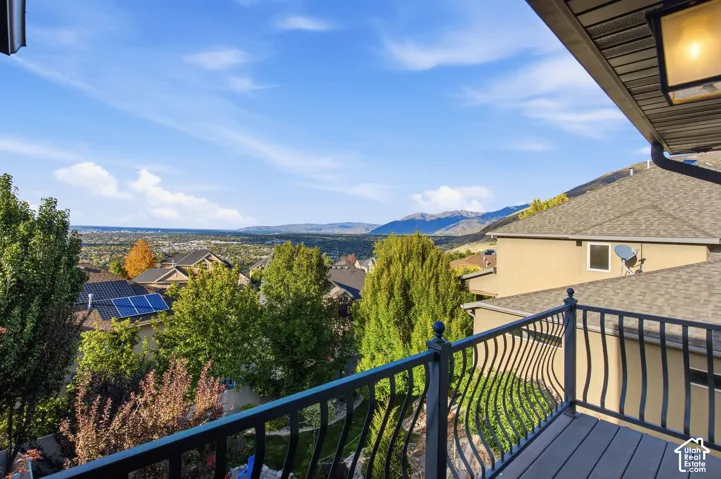 Covered balcony featuring black metal railings and composite decking, showcasing expansive mountain and valley scenery