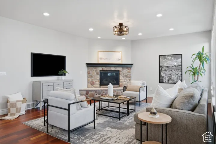 Corner fireplace with natural stone masonry, dark mantle, and raised hearth, complemented by wood-finish flooring and recessed lighting