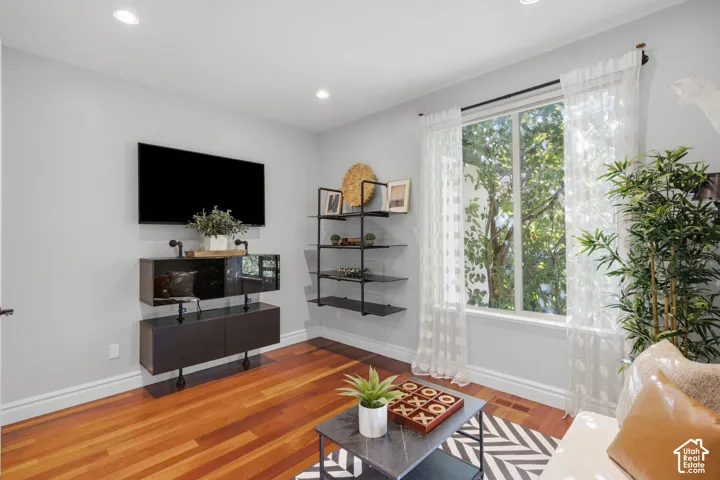Wood-finish flooring, recessed lighting, and a large sliding window with external tree canopy exposure