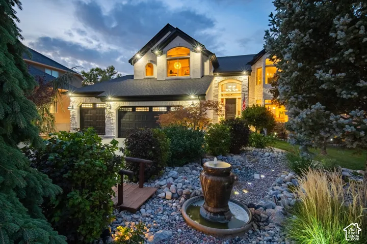 Stone facade residence with a multi-car garage, established landscaping, and a decorative water feature