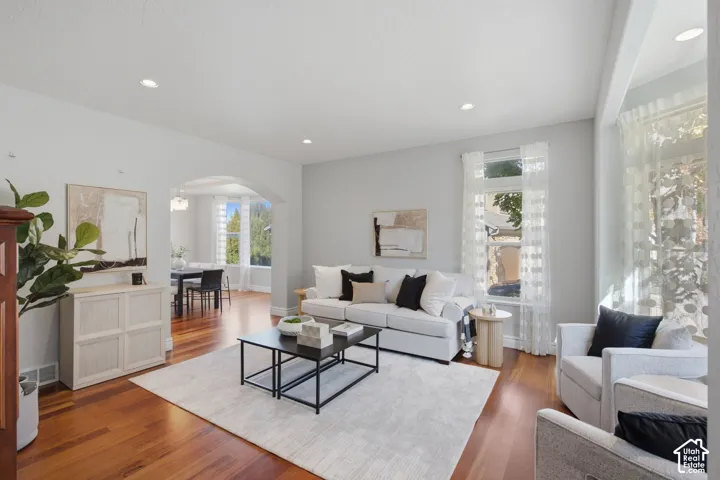 Living area featuring wood-finish flooring, recessed lighting, and a prominent arched entryway