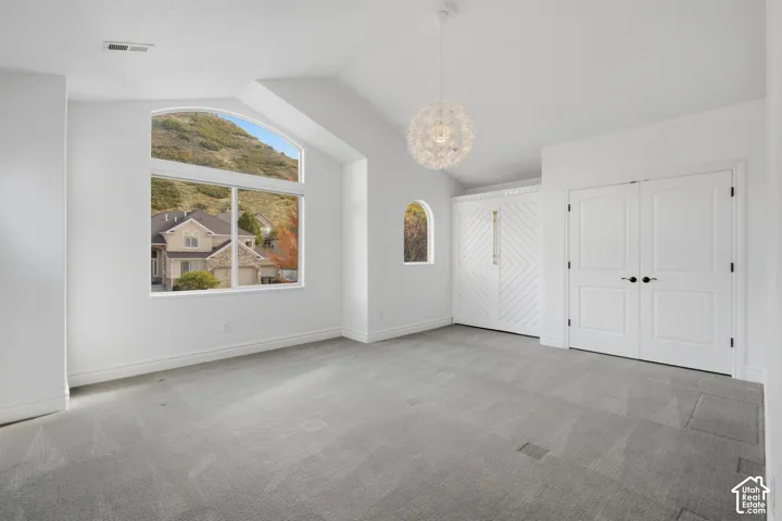 Vaulted ceilings, expansive arched windows, built-in cabinetry featuring chevron-patterned millwork, and wall-mounted pendant lighting