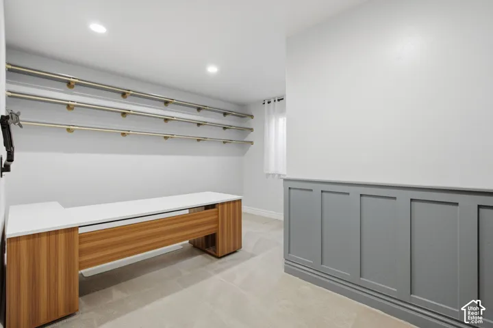 Built-in workstation featuring a solid surface countertop and wood-finish cabinetry, triple-tier wall-mounted shelving, wainscoting detail, and recessed ceiling lighting