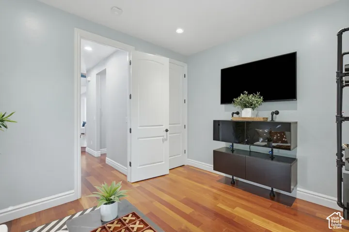 Hardwood flooring, recessed lighting, and wall-mounted multi-panel doors