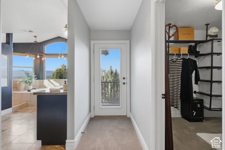 Entryway featuring an exterior glass-panel door, carpeted flooring, tile flooring in the open-concept room, arched window, and custom pipe-style wall shelving
