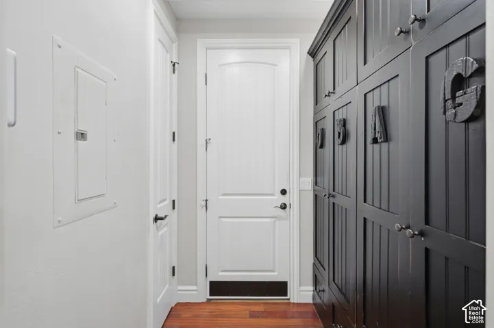 Built-in matte black cabinetry with vertical paneling and metal hardware, contrasting white arched-top interior door, and wood-finish flooring