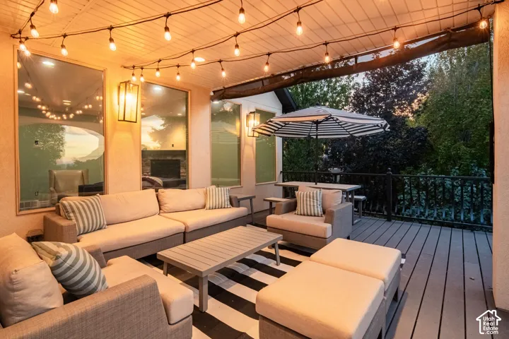 Covered outdoor patio with string lighting, paneled ceiling, dark wood-finish decking, and black metal railing