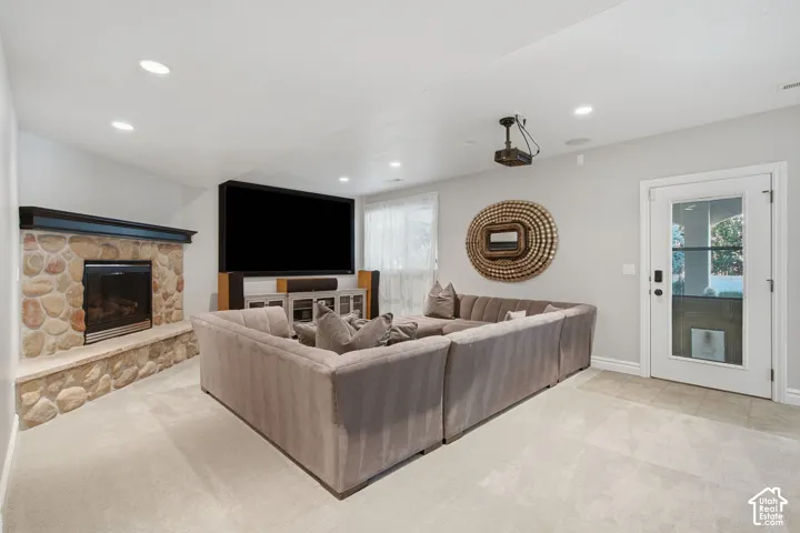 Corner fireplace with stone-veneer surround and timber mantel, recessed ceiling lighting, and exterior access door with glass pane