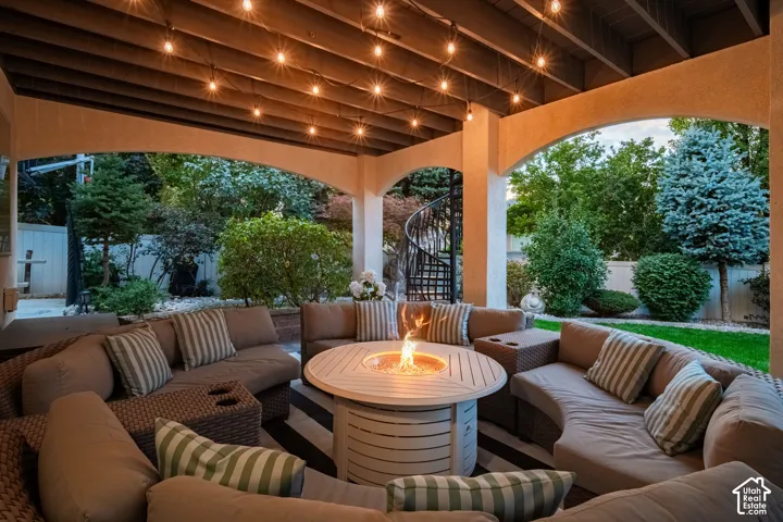 Covered patio with integrated string lighting, a gas fire pit, and a spiral staircase