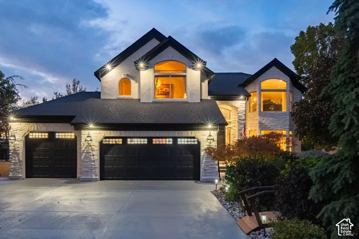 Stucco and stone exterior with arched windows, multiple gables, and a three-car garage