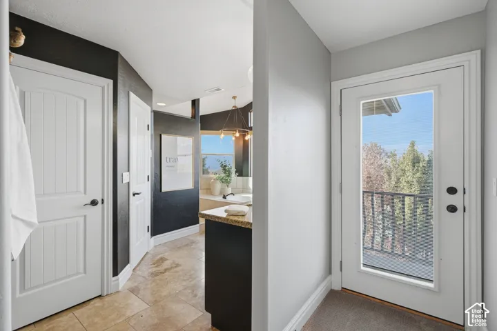 Tile flooring, solid core panel doors with matte black hardware, stone-surface countertop, and exterior glass-paneled door