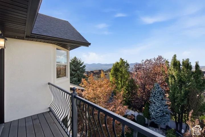 Covered exterior deck with wrought iron railing, stucco siding, and mountain backdrop
