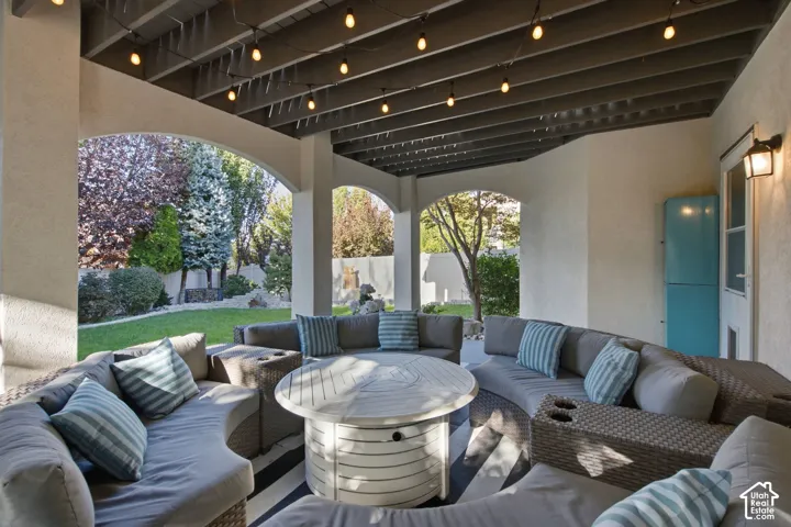 Covered patio featuring arched architectural openings, an exposed beam ceiling, and integrated wall-mounted lighting